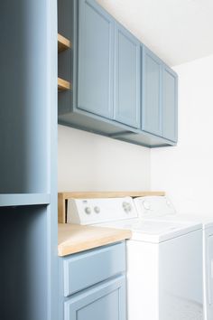 a washer and dryer in a room with blue cupboards on the wall