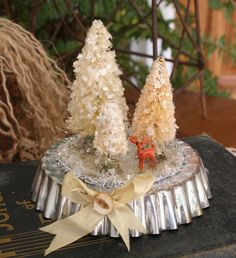 two small trees are sitting on top of an old book with ribbon around the edges