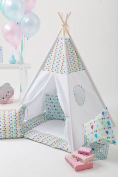 a teepee tent with balloons in the background and a basket full of toys next to it