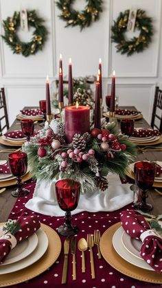 a christmas table setting with candles, plates and napkins