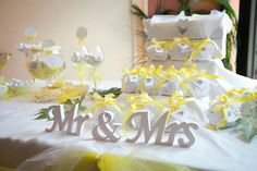 the table is set up for a wedding reception with yellow flowers and gifts on it