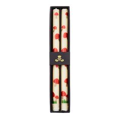 three candles with red and white designs in a black box