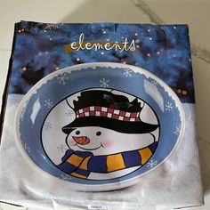 a bowl with a snowman painted on the front and bottom, sitting on top of a magazine