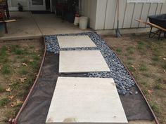 two stepping stones are laid out on the ground in front of a garage with an open door