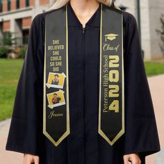 a woman wearing a black graduation gown with gold lettering