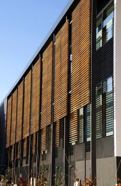 the side of a building with wooden slats on it's sides and plants in front