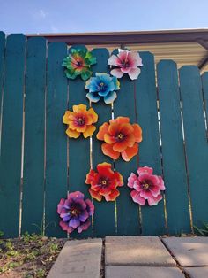 colorful paper flowers are hanging on the fence