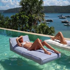 a woman laying on top of a blue and white striped chaise lounger next to a pool