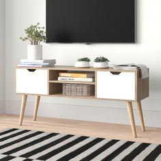 a tv is mounted on the wall above a wooden entertainment center with drawers and baskets