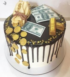 a cake decorated with money, gold and chocolate icing on a white tablecloth