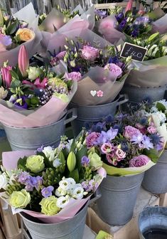 several buckets filled with different types of flowers