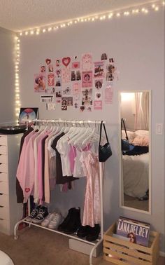 a closet with clothes hanging on the rack and lights strung from the wall above it