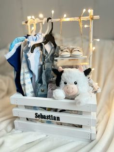 a stuffed cow is sitting in a crate with clothes and shoes on the shelf behind it