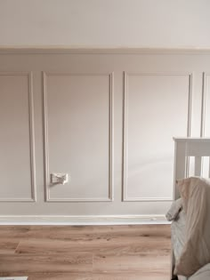 a baby crib in the corner of a room with white walls and wood floors