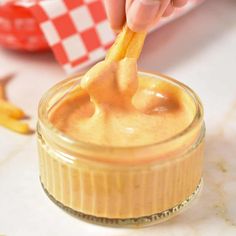 a person dipping some food into a jar