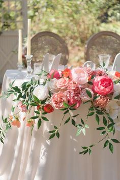 the table is set with flowers and candles for an elegant wedding reception in pinks, oranges and greens