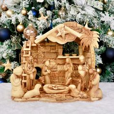 a wooden nativity scene in front of a christmas tree