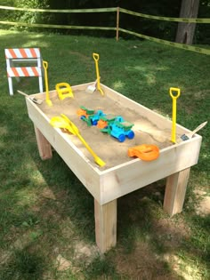 a sand table with toys in it on the grass