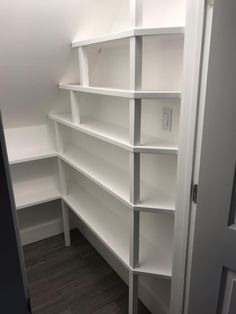 an empty white bookcase in the corner of a room