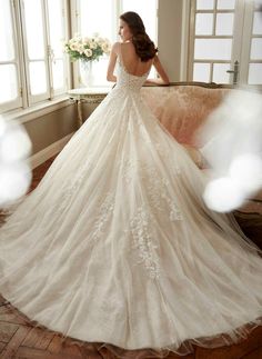 a woman in a wedding dress is sitting on a couch and looking out the window