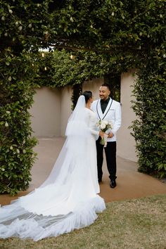 a bride and groom standing in front of an arch with greenery on the side