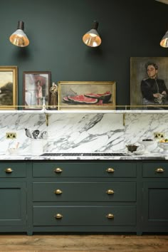 a kitchen with green cabinets and marble counter tops, gold pulls on the handles and brass knobs