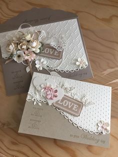 two handmade wedding cards with flowers and hearts on the front, one in grey and white