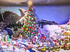 a christmas tree is in the middle of a snow - covered landscape with many toys