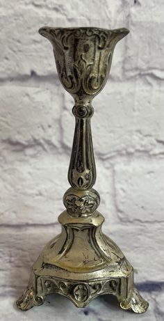 an ornate metal candle holder on a white brick wall