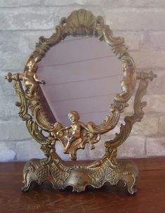 an ornate gold mirror sitting on top of a wooden table next to a brick wall