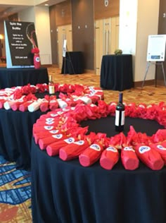 the table is set up with red wine bottles and decorations on it for an event