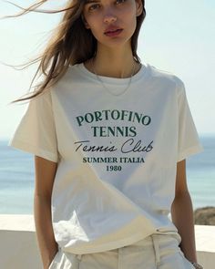 Grab your Vespa and your racket and get to the Portofino Tennis Club. Your retro passport to a stylish summer in Italia 1980. Ciao, bella! Unisex soft cotton crew neck t-shirt featuring a Portofino Tennis Club Italy 1980 graphic printed on the front. Fabrics: 100% cotton, 6.1 oz Made in: LA Models wearing S/M Vintage Logo Print Tops For Spring, Summer Tennis Tops With Short Sleeves, Summer Short Sleeve Tennis Tops, Short Sleeve Summer Tennis Tops, Short Sleeve Tennis Tops For Summer, Spring Tennis Tops With Graphic Print, Spring Tennis Crew Neck Top, Spring Tennis Tops With Crew Neck, Spring Crew Neck Tennis Tops