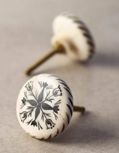 two white and black ceramic knobs on top of each other with flowers painted on them