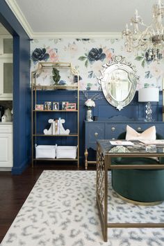 a living room filled with furniture and a chandelier above a coffee table in front of a blue wall