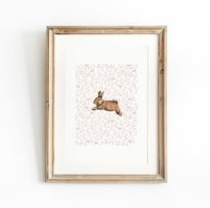 an animal is hanging on the wall in front of a white wall with a wooden frame