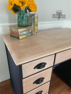 a wooden desk topped with two drawers and a vase filled with yellow sunflowers