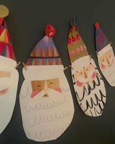 three paper santas hanging on a clothesline with hats and beards attached to them