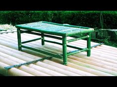 a green coffee table sitting on top of a wooden floor next to a lush green bush