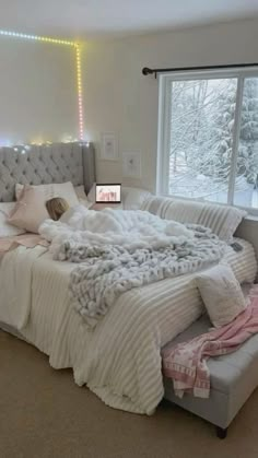 a bedroom with a large bed and lots of blankets on the top of it, next to a window