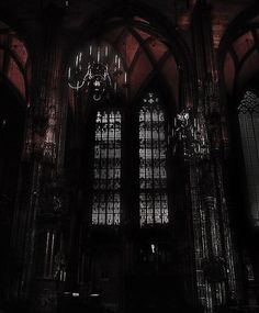 the chandelier is hanging from the ceiling in this gothic - style building with stained glass windows