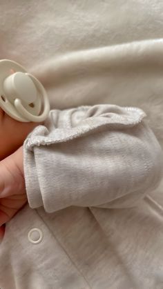 a baby is laying down with a pacifier in its mouth and wearing a white shirt