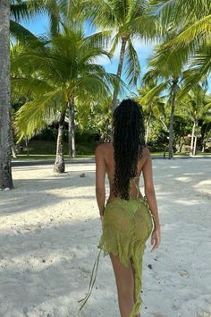 a woman standing on top of a sandy beach next to palm tree covered trees and white sand