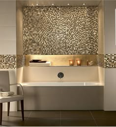 a bath tub sitting next to a white chair in a room with tiled walls and floor