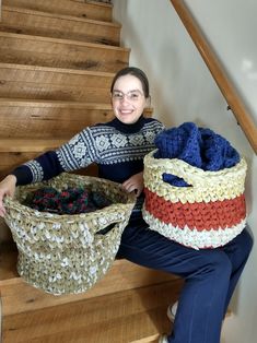 a woman sitting on the stairs holding two baskets