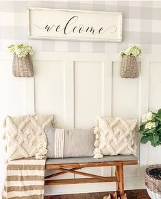 a bench with some pillows on it and a sign that says welcome above the bench