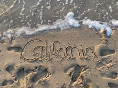 the word california written in sand at the beach