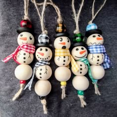 six snowmen are hanging from twine on the wall, and one is wearing a scarf