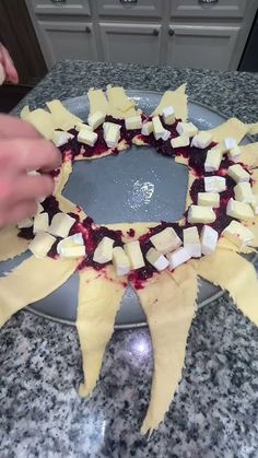 someone is decorating a plate with cheese and cranberry toppings on it