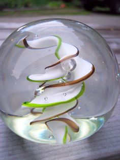 a glass vase filled with white and green flowers on top of a wooden table next to grass