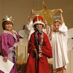 three children dressed up in costumes standing on stage with one holding a star above his head